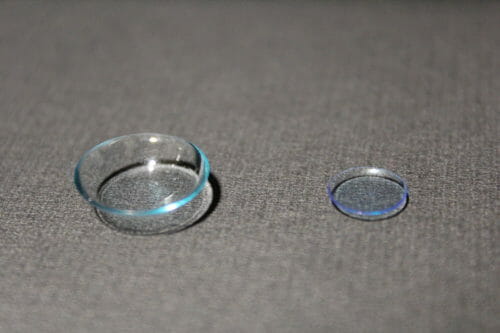 A scleral lens sits alongside a much smaller traditional gas permeable lens.